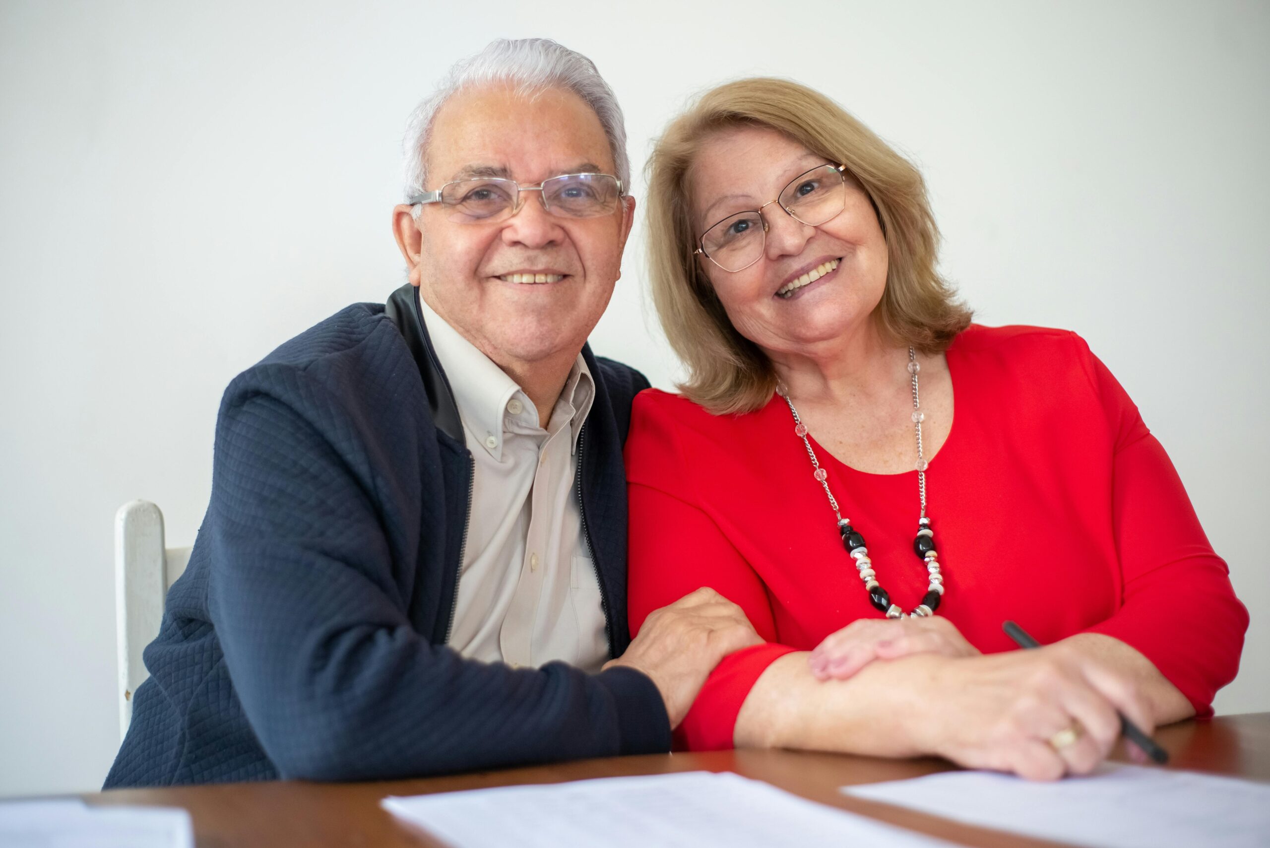 Elderly couple embracing and signing papers, sharing a warm and happy moment together.